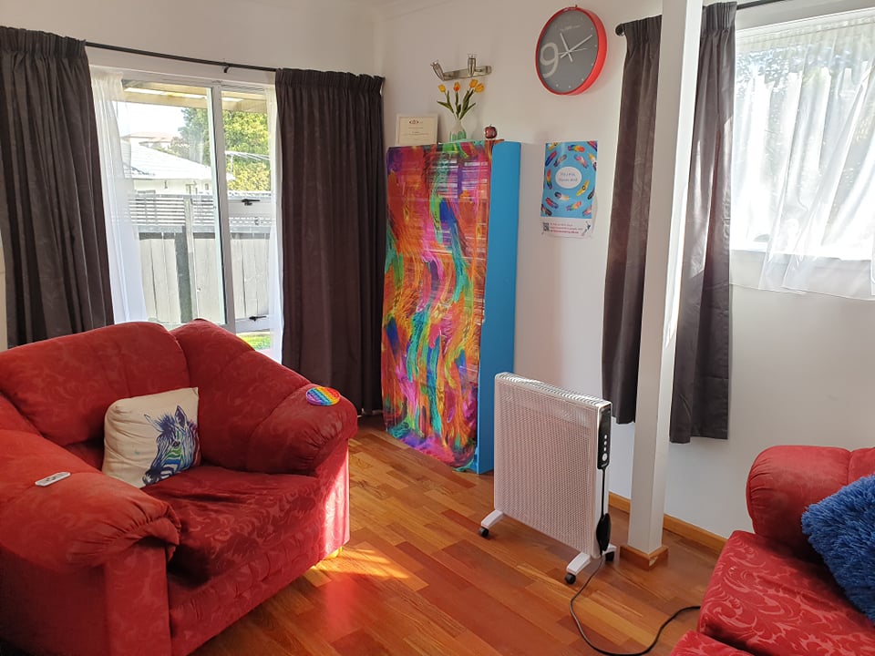 Warm room with comfortable red sofa and chair, a blue bookcase, and wooden floors